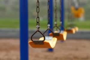 Closeup view of yellow swings on a playground swing set.