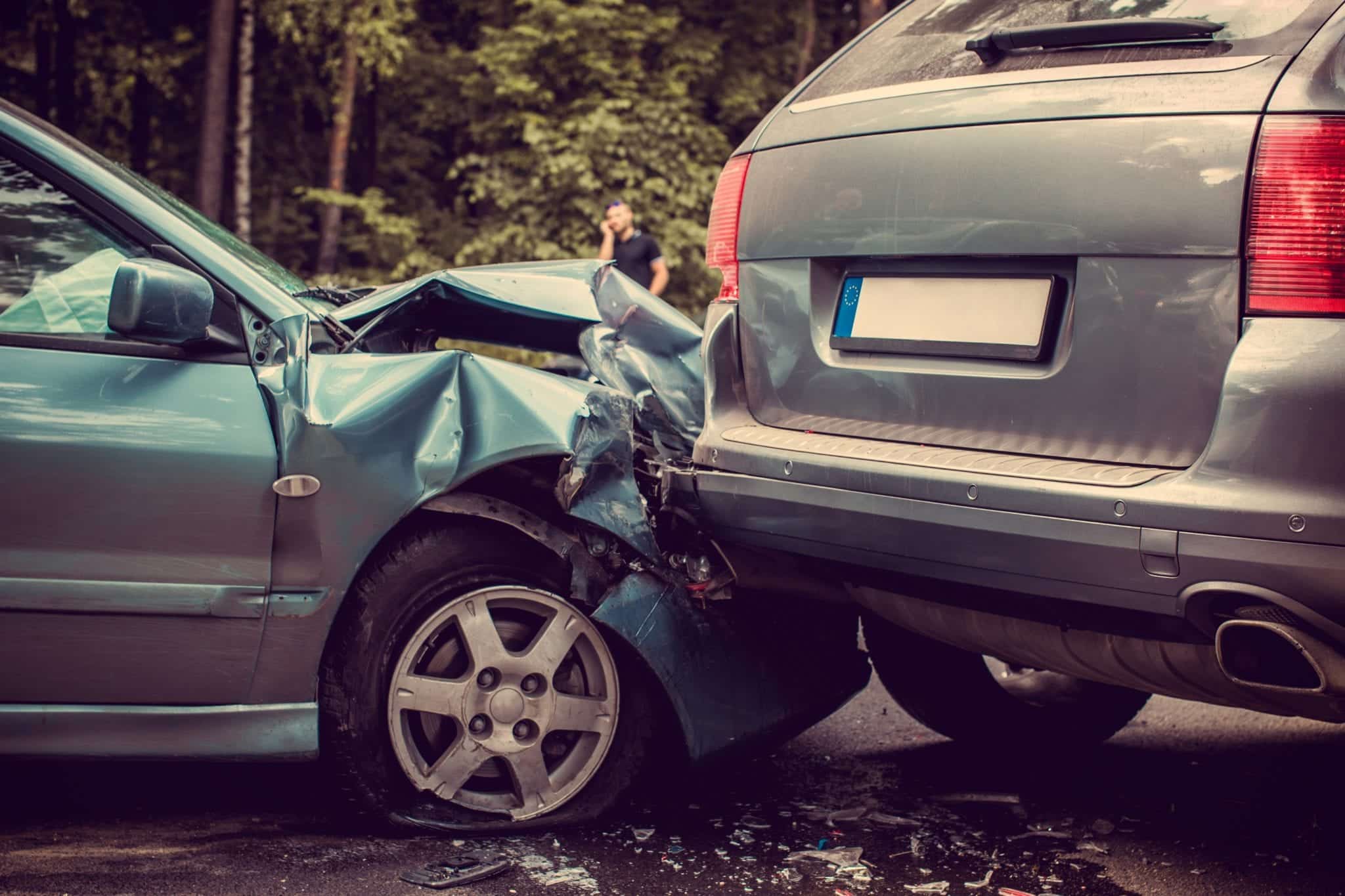 A close-up of a wreck scene showing a teal car that has rear ended a gray SUV.