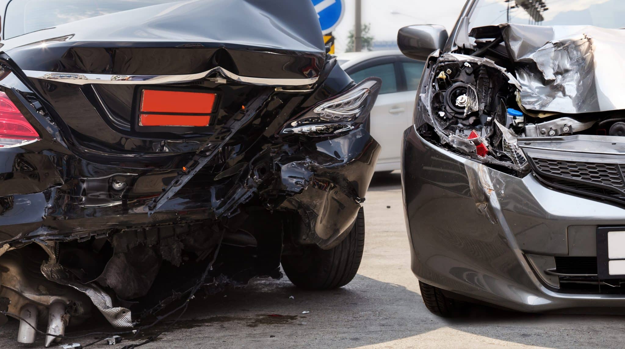 Two severely damaged cars, the back of a black car smashed in and the front of a gray car smashed in.