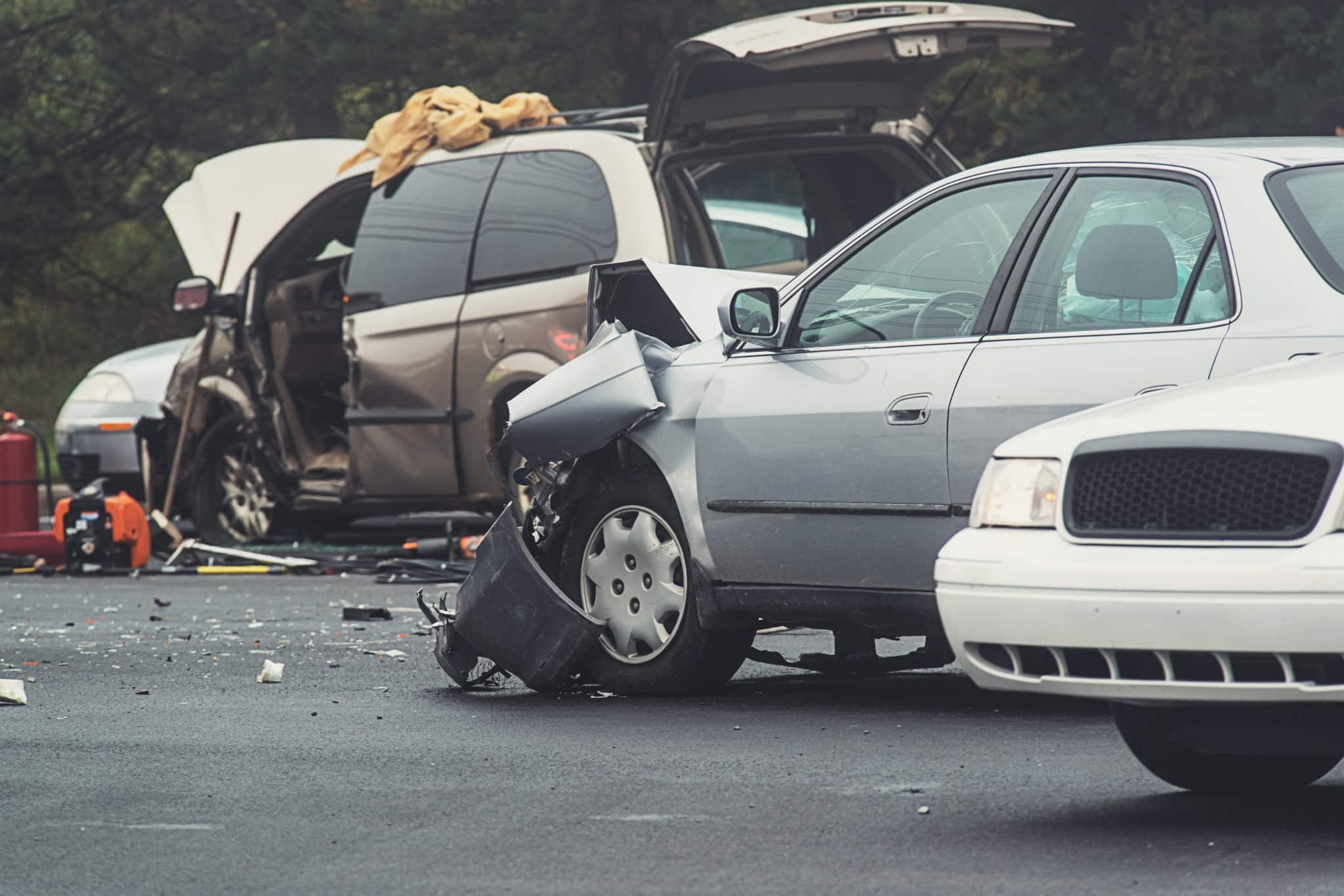 Multiple vehicles with severe collision damage at the scene of a crash involving an uninsured driver.