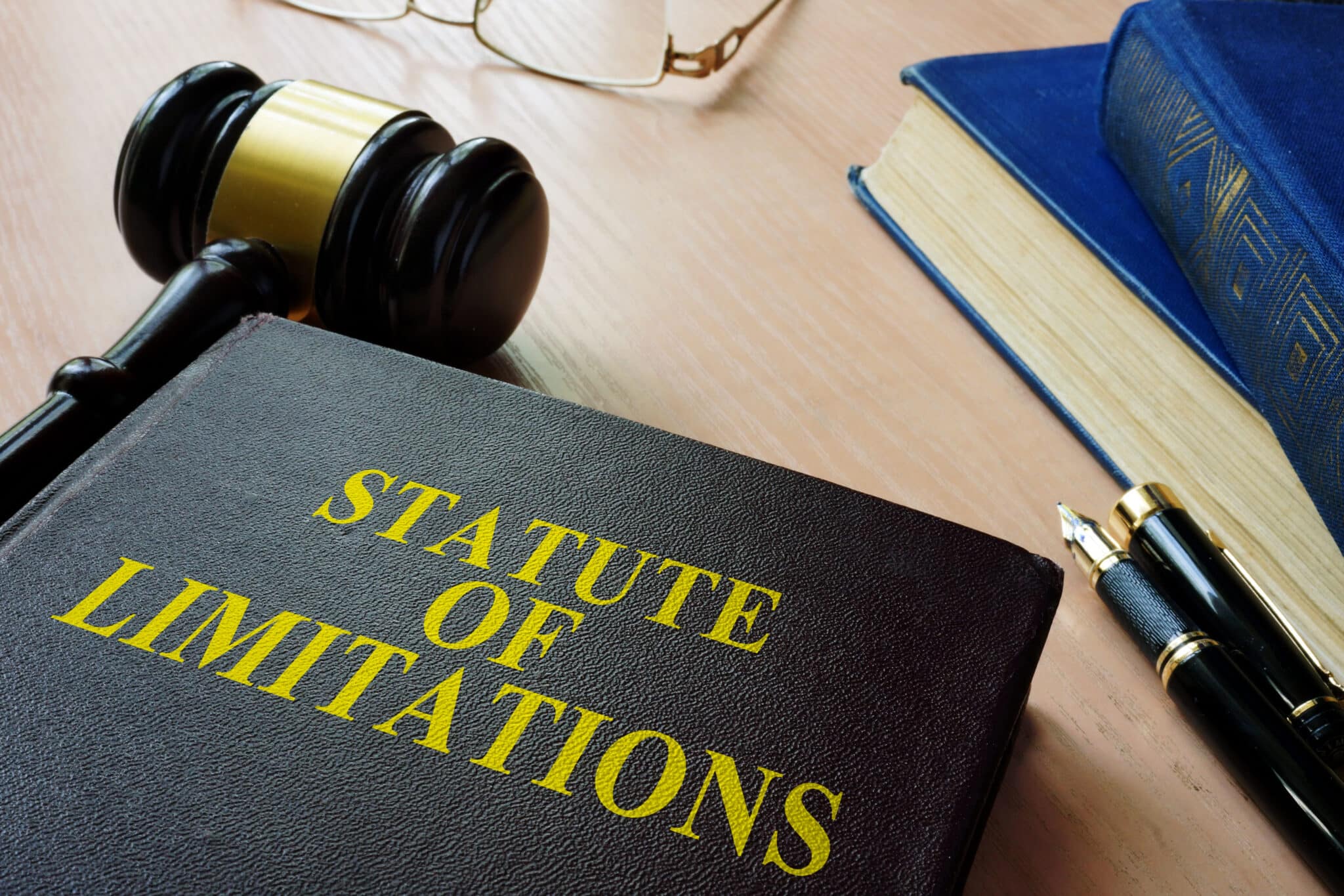 Legal book titled "Statute of Limitations" next to a gavel, law books, and a fountain pen on a lawyer’s desk in Kennesaw Georgia.