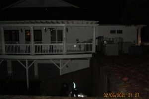 A white building with a deck, without any lights on, in the night.